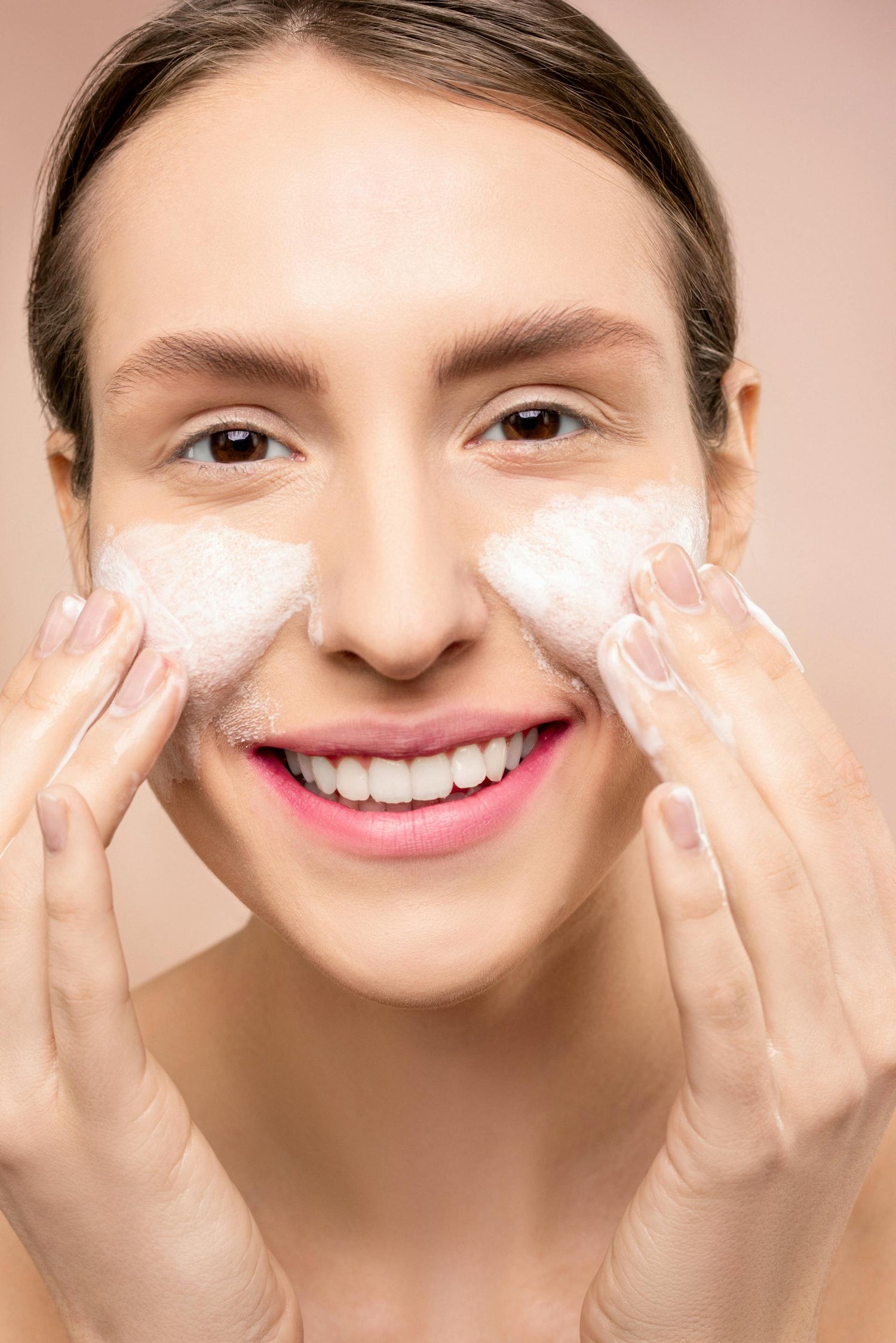 Mujer lavando su rostro con un limpiador facial en espuma, técnica correcta de limpieza dermatológica