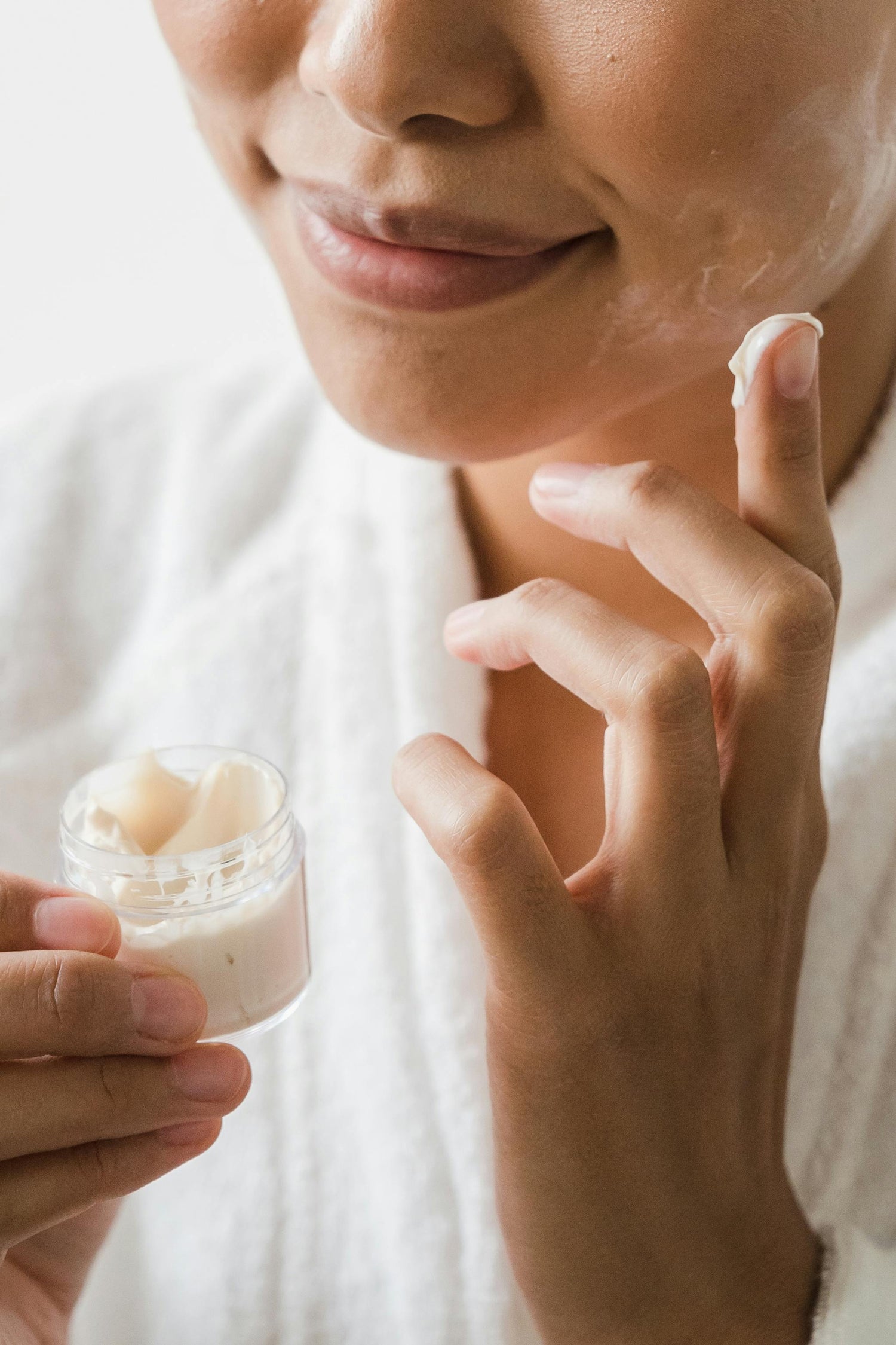 Mujer aplicando crema hidratante en el rostro como parte de su rutina dermatológica de reparación de barrera cutánea