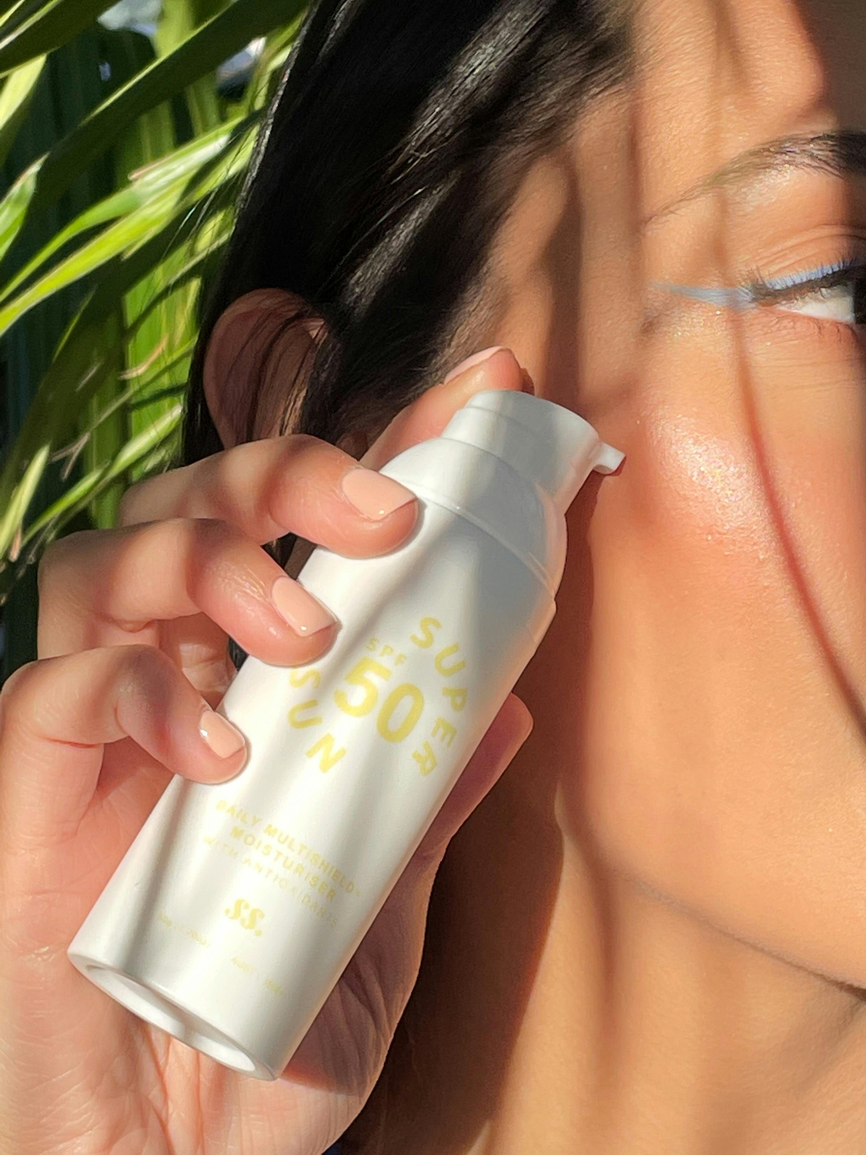Mujer sosteniendo un protector solar SPF 50, fotoprotección diaria recomendada para piel grasa y con tendencia acneica